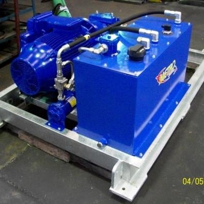 Blue hydraulic power unit with motor and pump on steel base in workshop