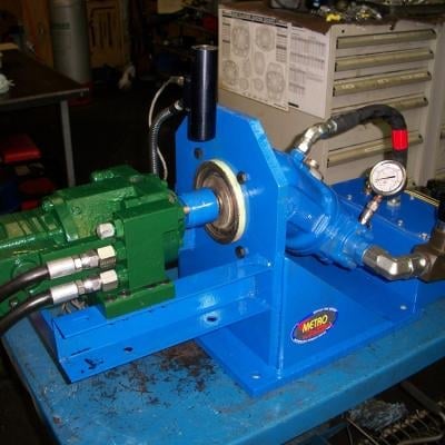 Hydraulic pump assembly with manifold block and pressure gauge on workbench